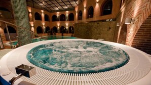 A hot tub in a spacious indoor area with arched ceilings and brick walls. - Hotel Doña Teresa (La Alberca)