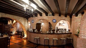 A bar area with a brick wall, wooden beams, and a counter with stools. - Hotel Doña Teresa (La Alberca)