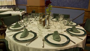 A dining table set with green napkins, plates, and cutlery, surrounded by chairs. - Hotel Clemente (Barbastro)