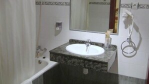 A bathroom with a white sink, a mirror, a towel rack, and a shower curtain. - Hotel Clemente (Barbastro)