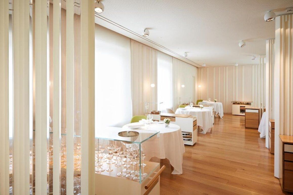 A spacious dining area with multiple tables, each set with white tablecloths and glassware.