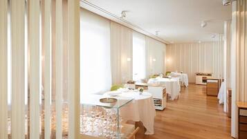 A spacious dining area with multiple tables, each set with white tablecloths and glassware.