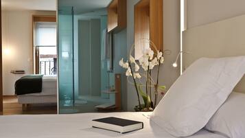 A modern bedroom with a bed, a bedside book, and a vase with white flowers.