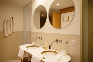 Une salle de bain moderne avec deux lavabos, un grand miroir et une douche à l’italienne.