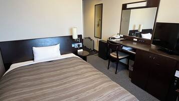 Une chambre d’hôtel équipée d’un lit, d’un bureau, d’une chaise, d’une télévision et d’un miroir.