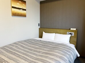 A hotel room with a bed, a headboard with a control panel, a wall-mounted artwork, and a plain wall. - Hotel Route-Inn Natori (Natori)