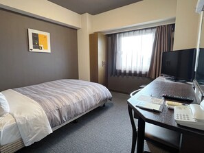 A hotel room with a bed, a desk with a telephone and remote control, a television, and a window with curtains. - Hotel Route-Inn Natori (Natori)