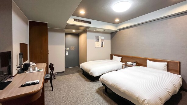 A hotel room with two beds, a desk with a chair, a TV, and a minibar. - Hotel Route-Inn Dai-Ni Nagano (Nagano)