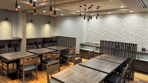 A modern restaurant interior with wooden tables and chairs, pendant lighting, and a brick accent wall. - Hotel Route-Inn Dai-Ni Nagano (Nagano)