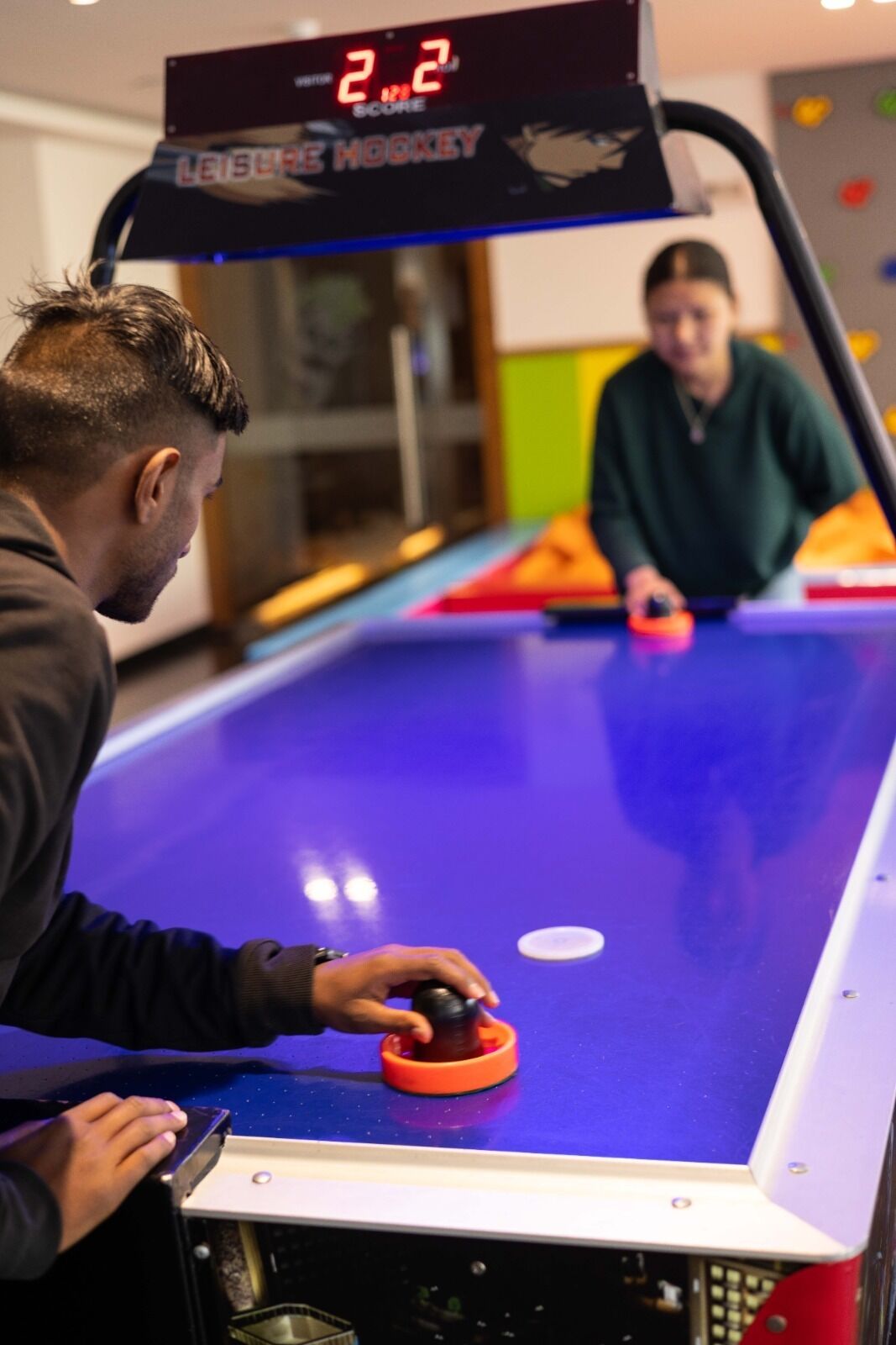 A table hockey game with a digital scoreboard displaying a score of 2-2.