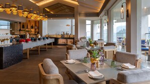 Een modern restaurant met een lange toonbank, meerdere eettafels en stoelen.