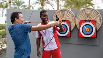 Two people practicing archery with targets in the background.