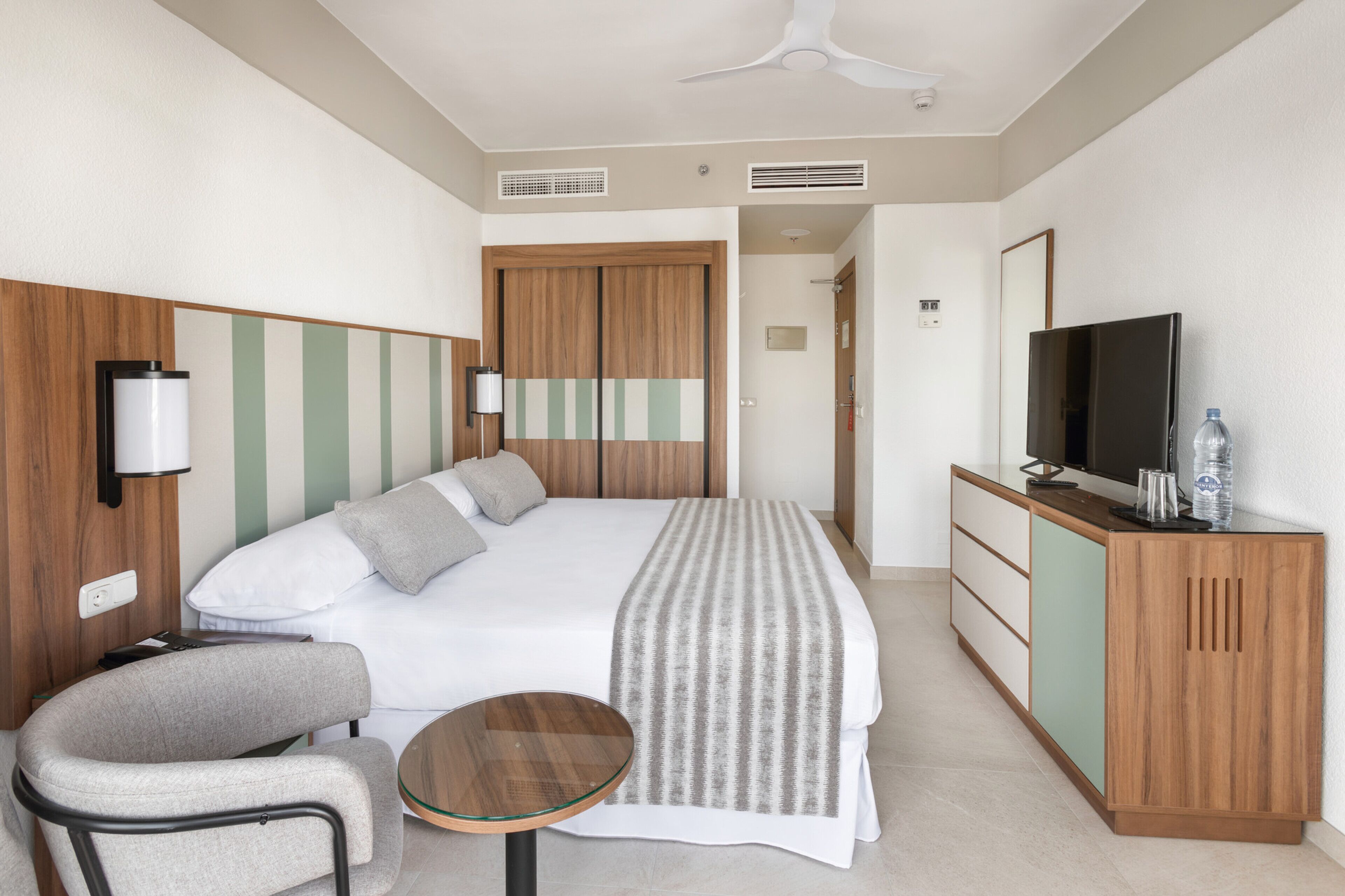 A hotel room with a bed, a TV, a desk, and a chair.