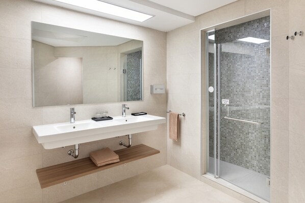 Une salle de bain moderne avec un lavabo blanc, un miroir et une douche en verre.