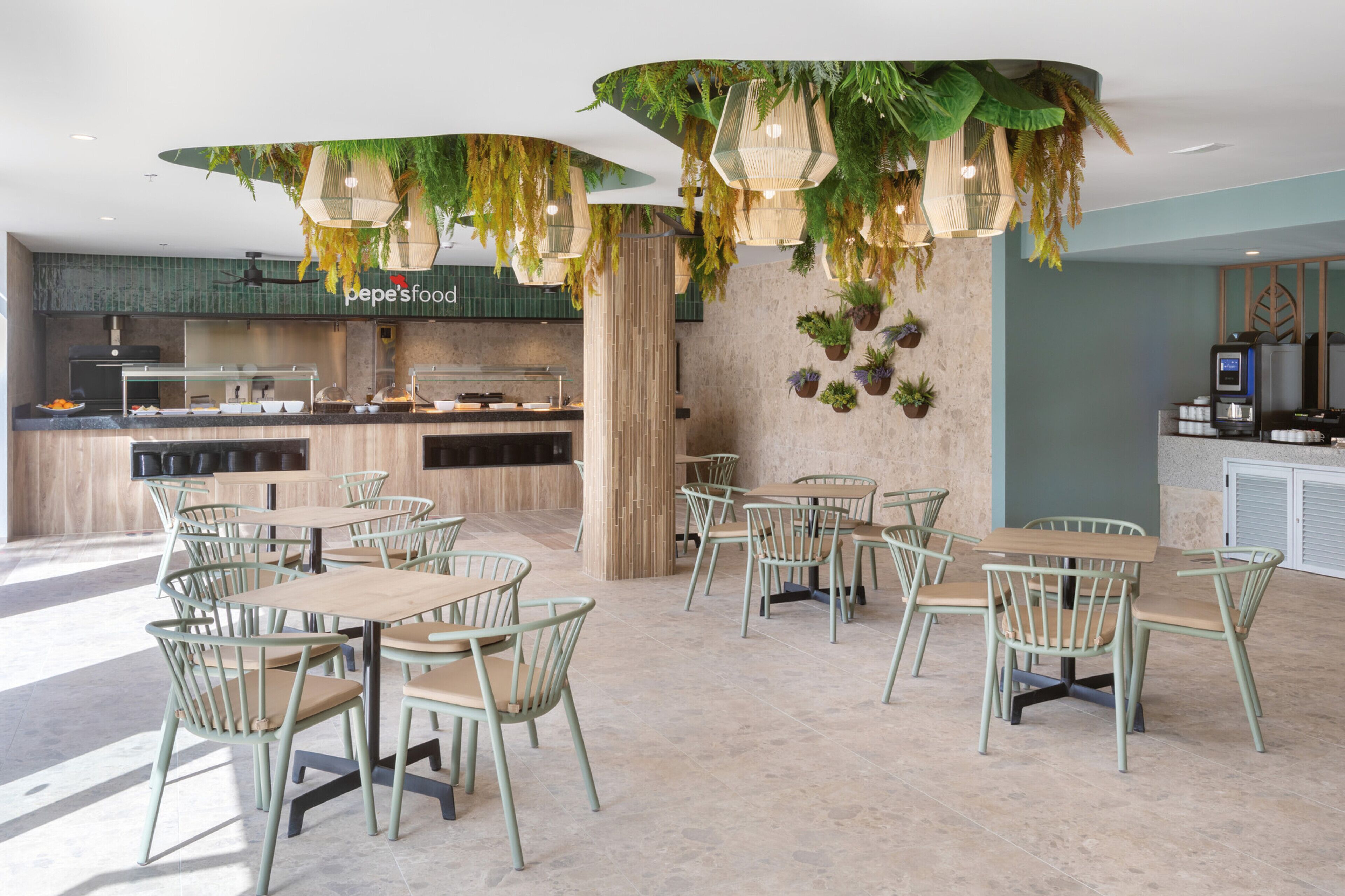 A restaurant with a modern interior, featuring a counter with a menu, multiple seating areas with tables and chairs, and decorative hanging plants.