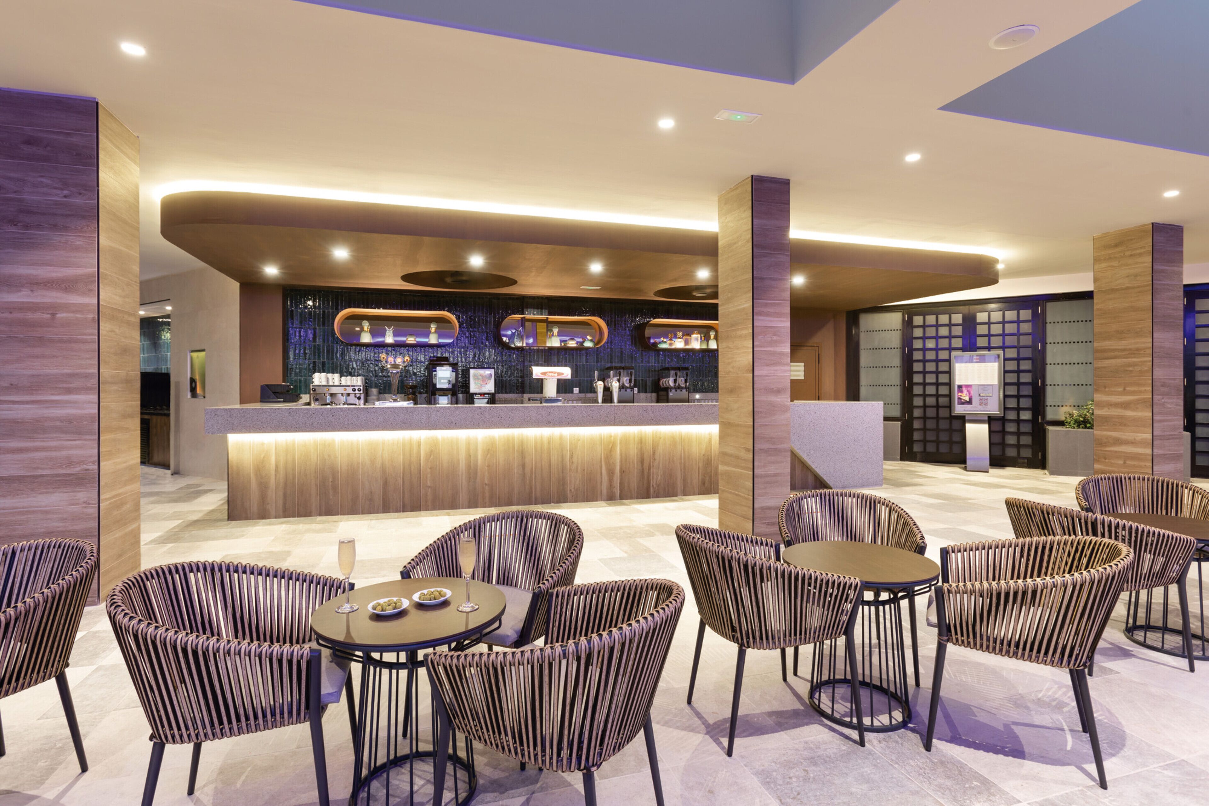 A modern lobby with a reception desk, seating area, and decorative wall panels.