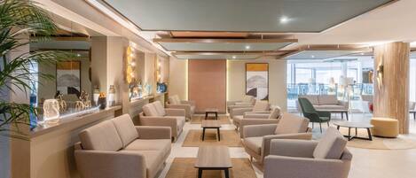 A modern lounge area with sofas, tables, and a bar area with decorative items.