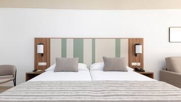 Una cama doble con una manta a rayas, dos mesitas de noche con lámparas, un cabecero de madera y una silla.