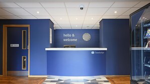 A reception desk with a clock, a 'hello & welcome' sign, and a 'private' sign on a door. - Travelodge Falkirk (Falkirk)
