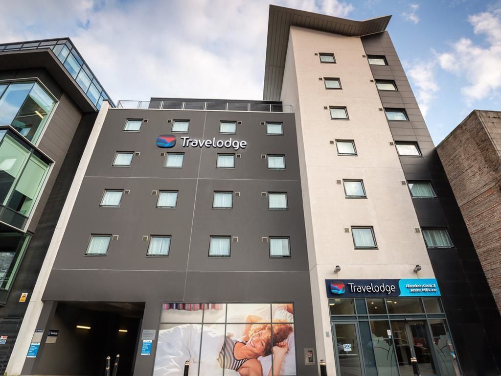 Um hotel Travelodge com fachada moderna, várias janelas e entrada destacada.