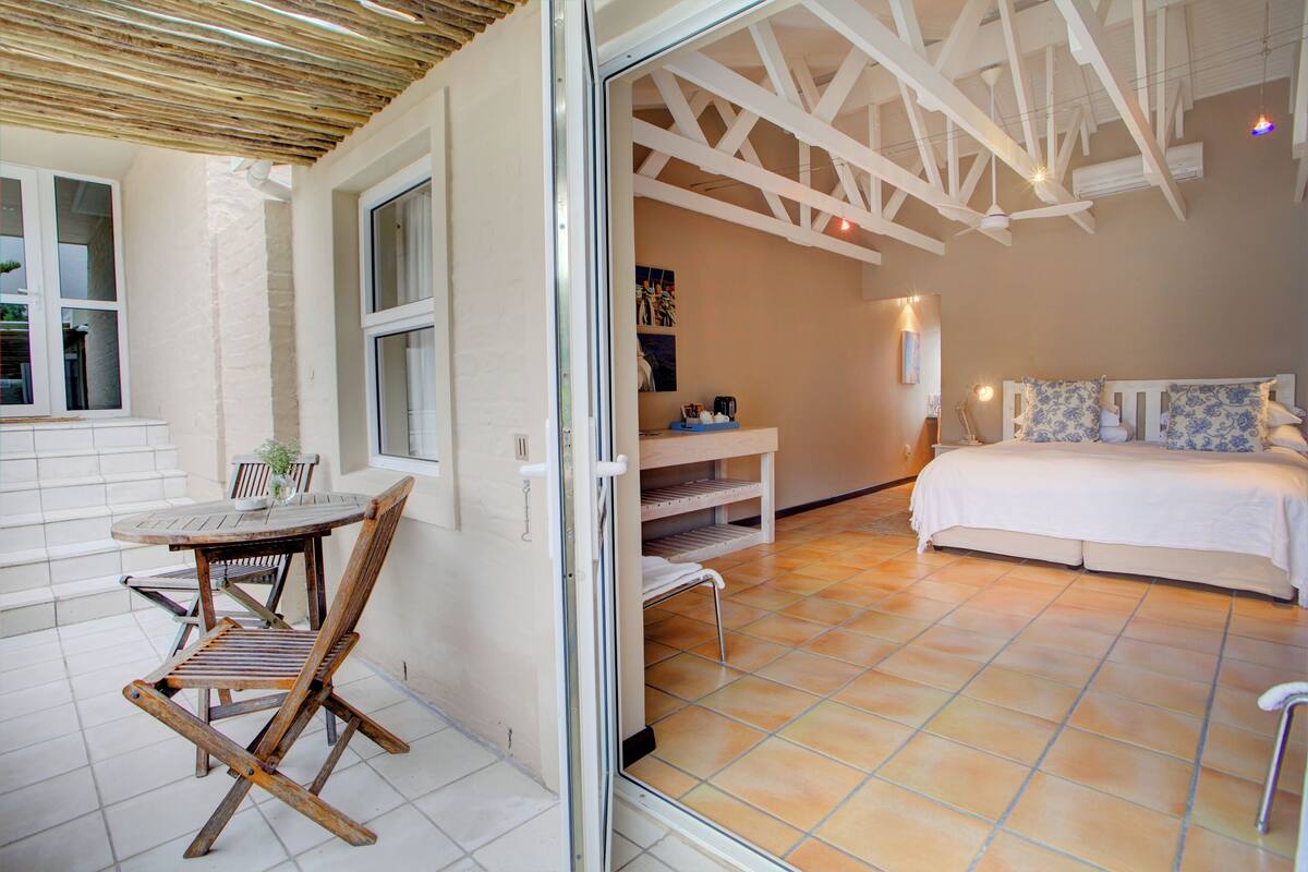 A room with a bed, a small table with chairs, and a bench.