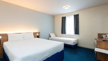 A hotel room with a large bed, a smaller bed, a desk, and a window with curtains.