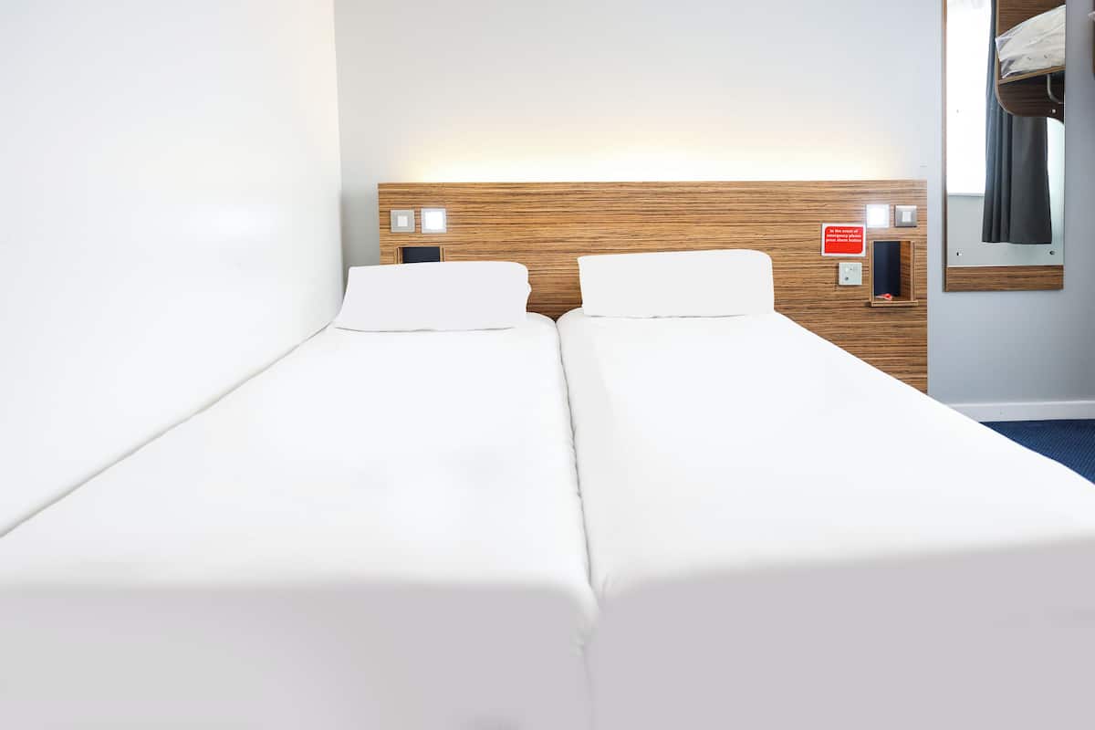 Ein Doppelbett mit weißer Bettwäsche in einem Hotelzimmer.