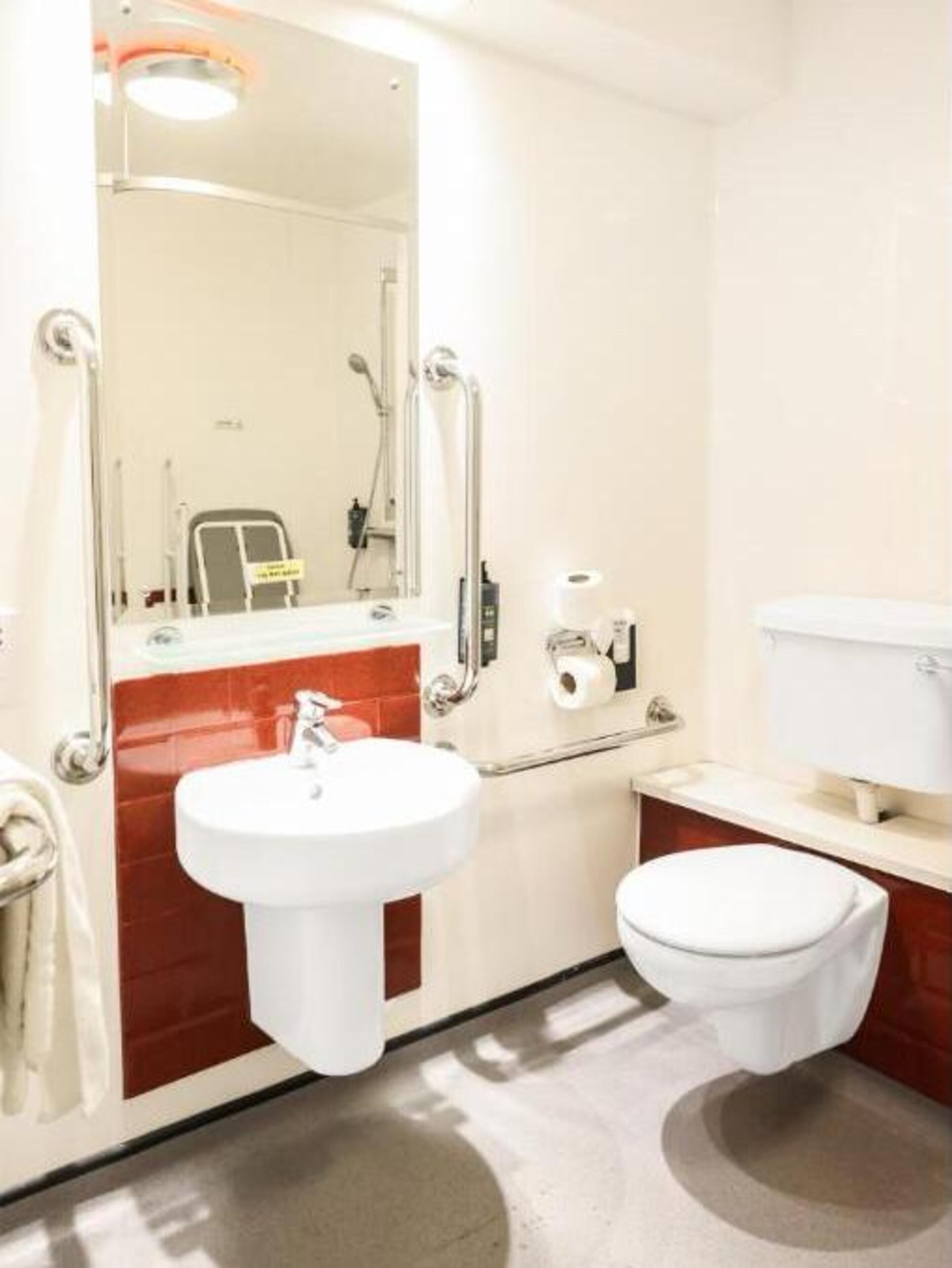 A compact bathroom with a white sink, a toilet, and a mirror.