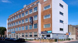 Un hôtel Travelodge à la façade en briques, doté de nombreuses fenêtres et d’un panneau indiquant les emplacements de stationnement dans les rues William et Cecil.