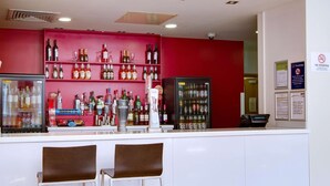 Un espace bar avec des étagères remplies de bouteilles d’alcool, un réfrigérateur et un distributeur automatique.