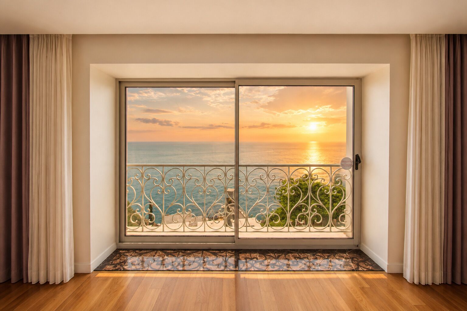 Et værelse med en stor skydedør, der fører ud til en balkon med havudsigt i solnedgang.