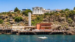 A coastal resort with a pier, beach umbrellas, and a pool area.