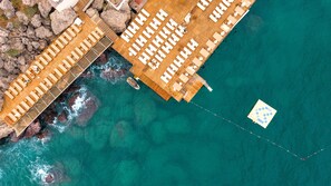 An aerial view of a resort with multiple wooden deck areas, some with lounge chairs and umbrellas, and a clear turquoise sea. - Massimo Hotel - Adults Only 'Ex La Boutique Hotels (Antalya)