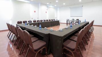 A conference room with a long table, chairs, water bottles, and a projector screen.