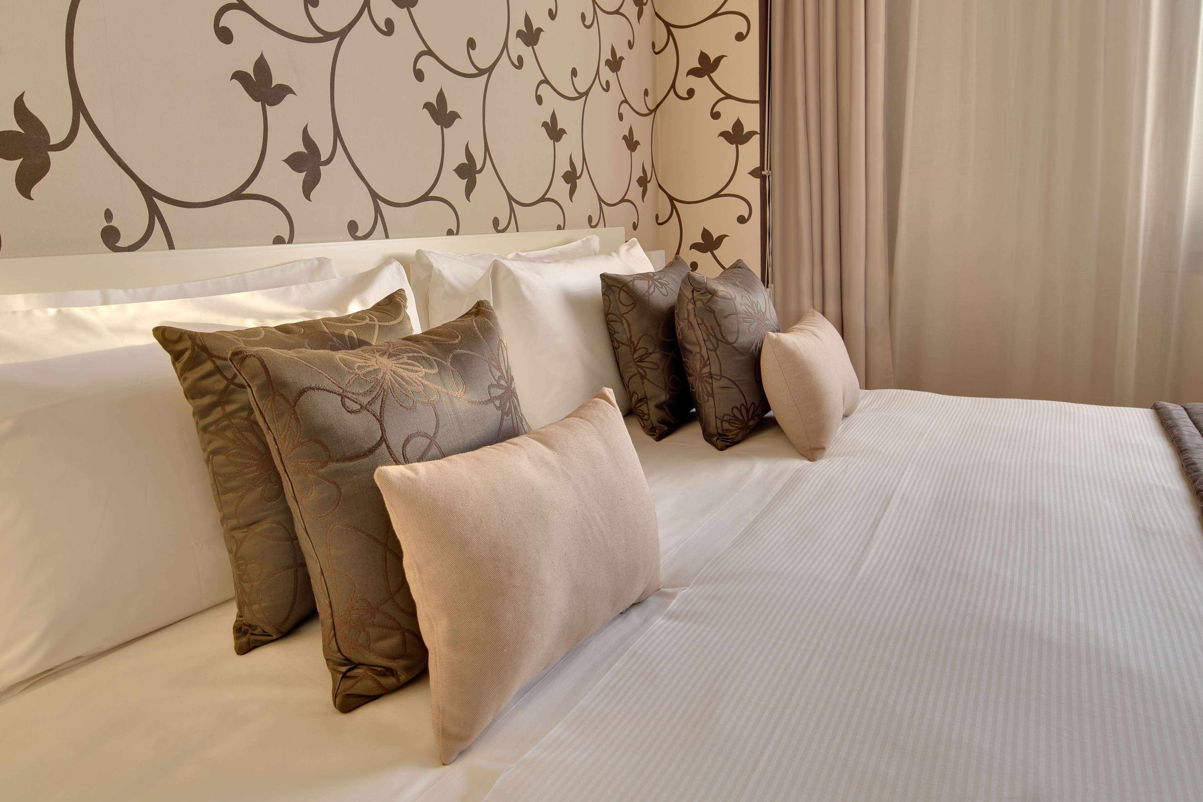 A neatly made bed with multiple pillows and a decorative headboard.