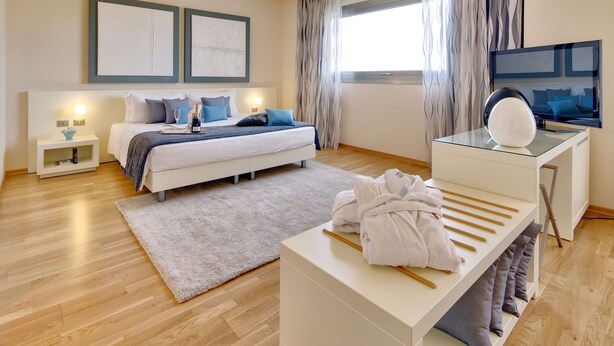 A modern bedroom with a bed, bedside tables, a vanity with a mirror, and a large window with curtains. - Best Western Plus Leone di Messapia Hotel & Conference (Lecce)