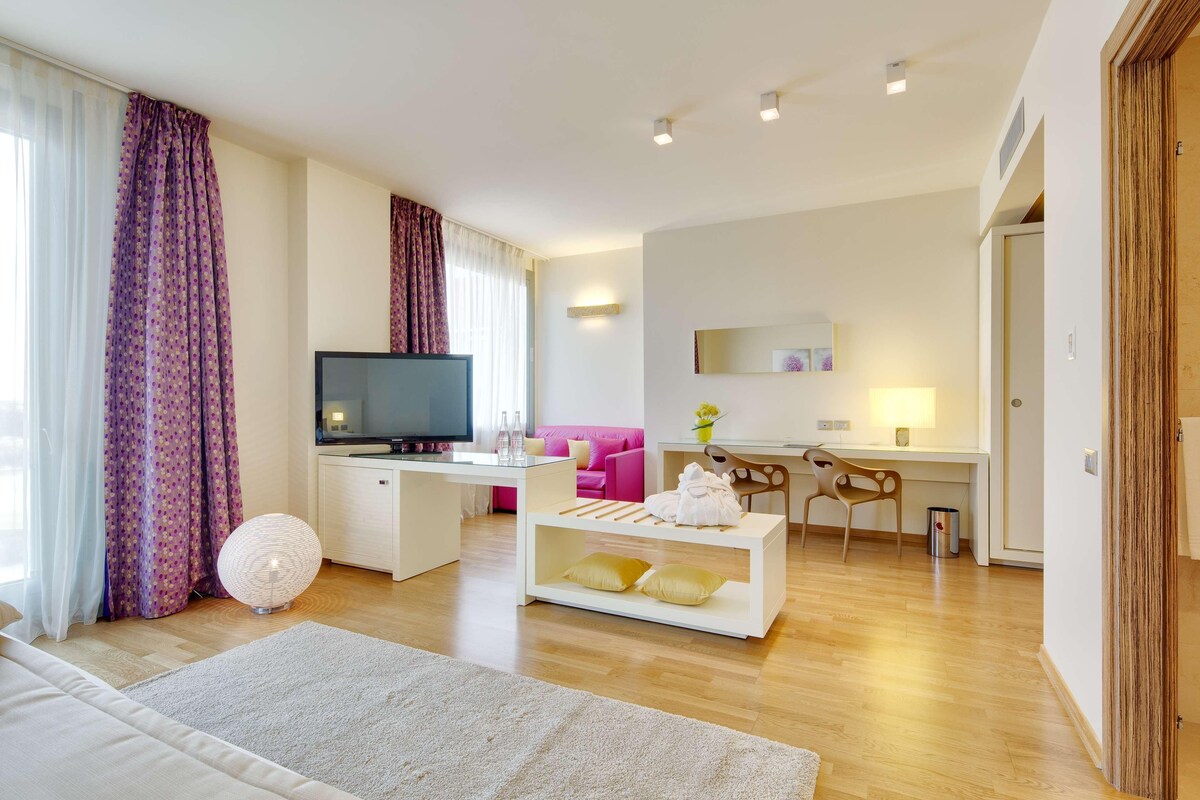 A modern living room with a flat-screen TV, a sofa, a coffee table, and a desk with a chair.