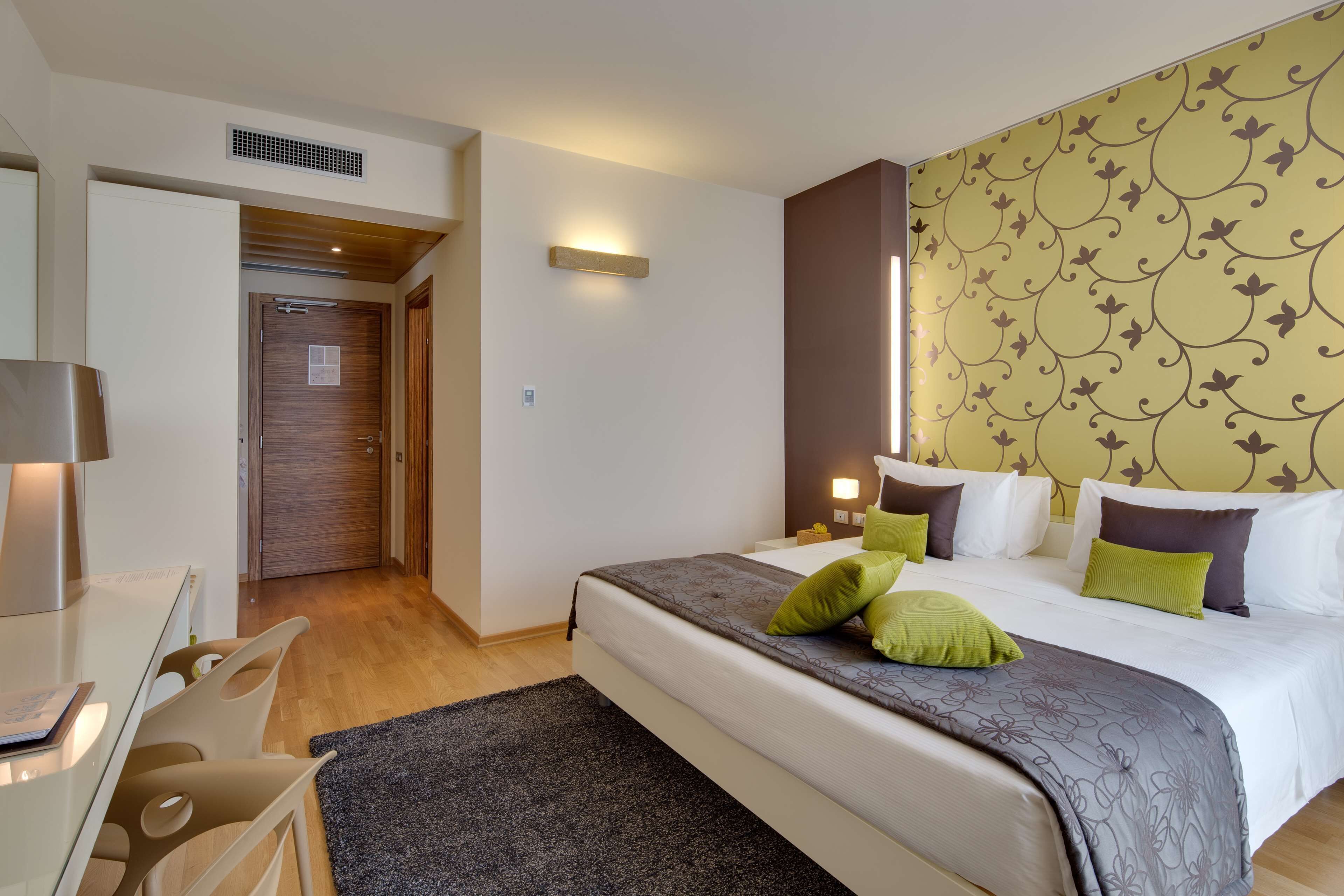 A hotel room with a bed, bedside tables, a desk, and a chair.