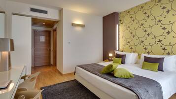 A hotel room with a bed, bedside tables, a desk, and a chair.