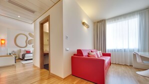 A modern living room with a red sofa, a white desk, and a large window with curtains. - Best Western Plus Leone di Messapia Hotel & Conference (Lecce)