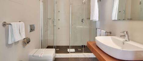Un baño moderno con dos lavamanos, cabina de ducha de vidrio y un espejo grande.