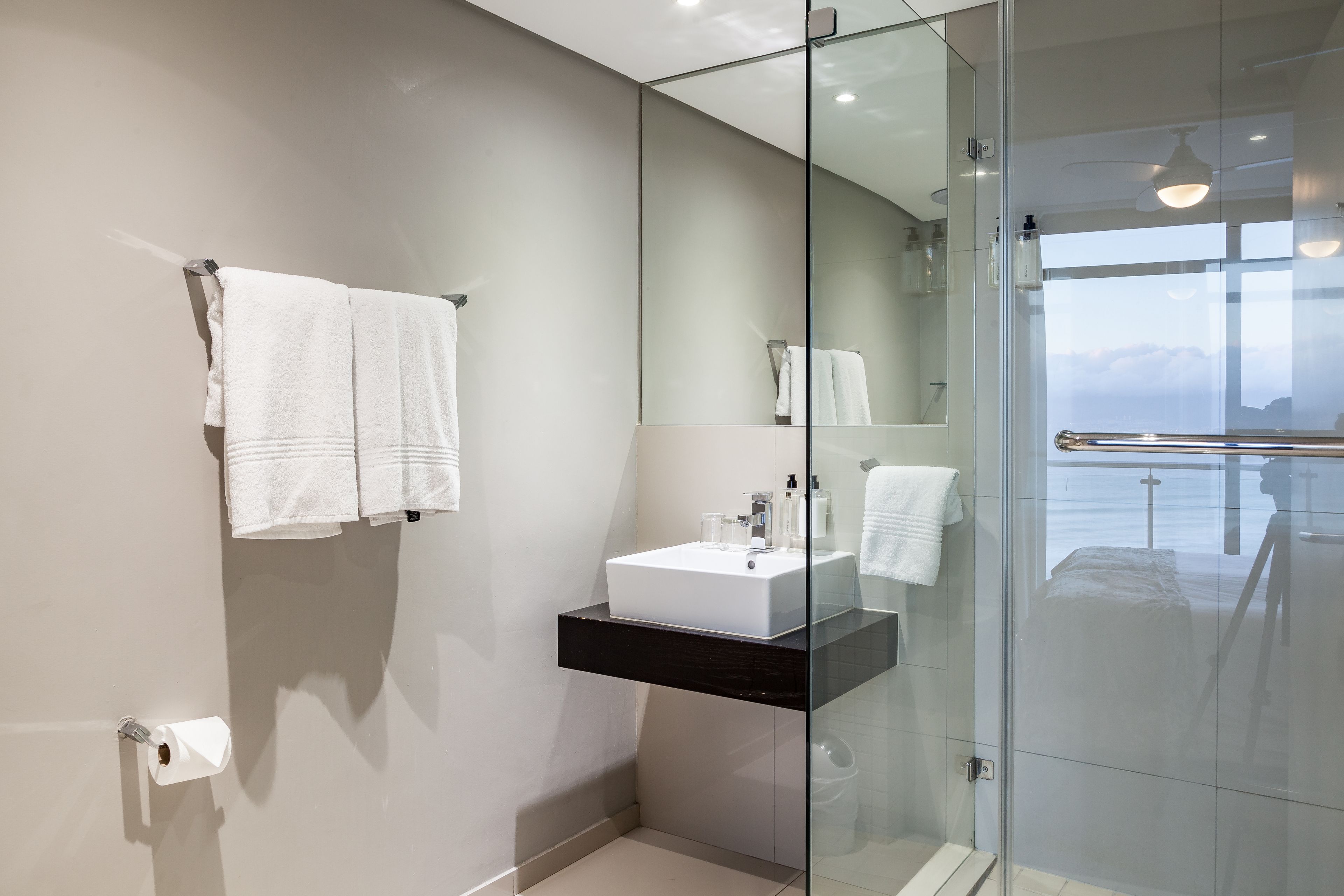 A modern bathroom with a glass-enclosed shower, a white sink, and a large mirror.