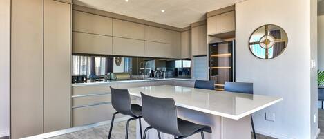 Une cuisine moderne dotée d’un grand îlot central, de tabourets de bar et d’un miroir décoratif.