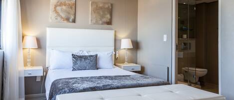 A modern bedroom with a large bed, two bedside tables, and a glass-enclosed shower.