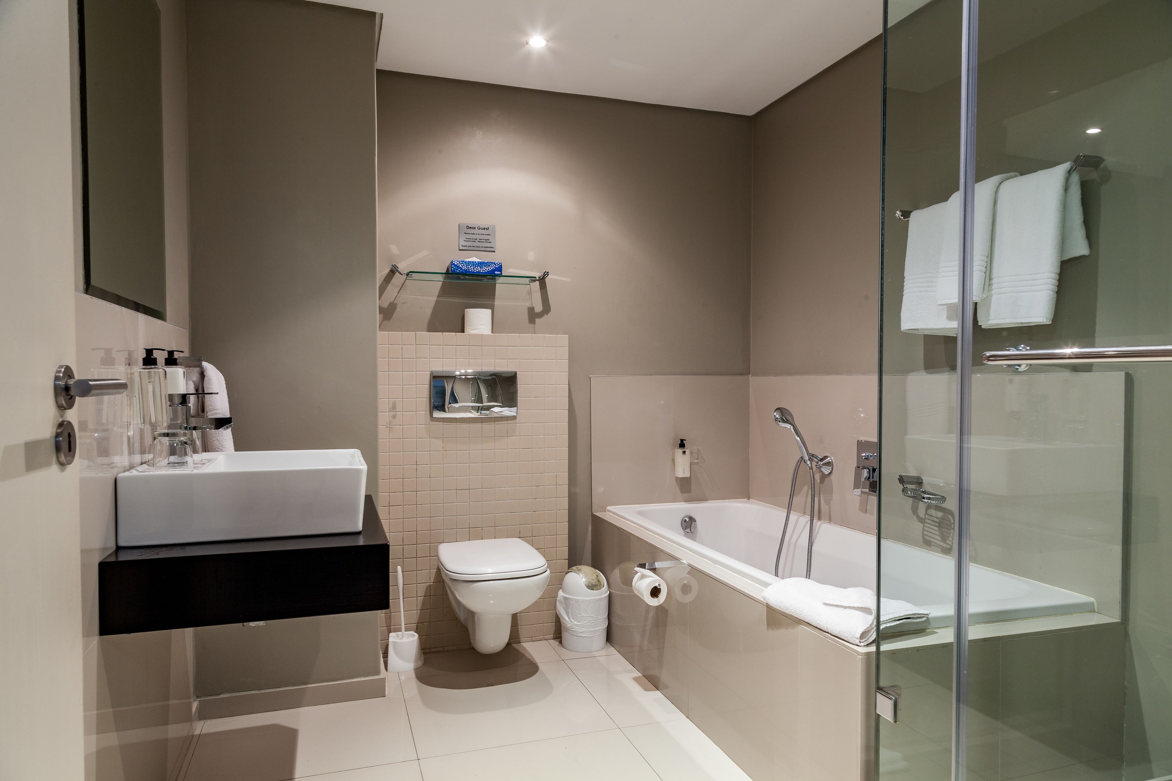A modern bathroom with a glass-enclosed shower, a white sink, and a toilet.