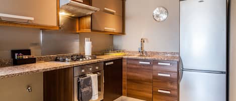 A modern kitchen with wooden cabinets, stainless steel appliances, and a clock on the wall.