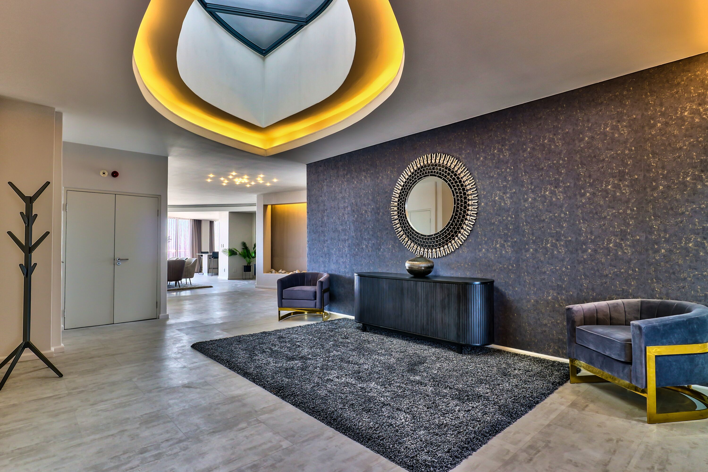 A modern lobby with a dark textured wall, a large mirror, and two armchairs.