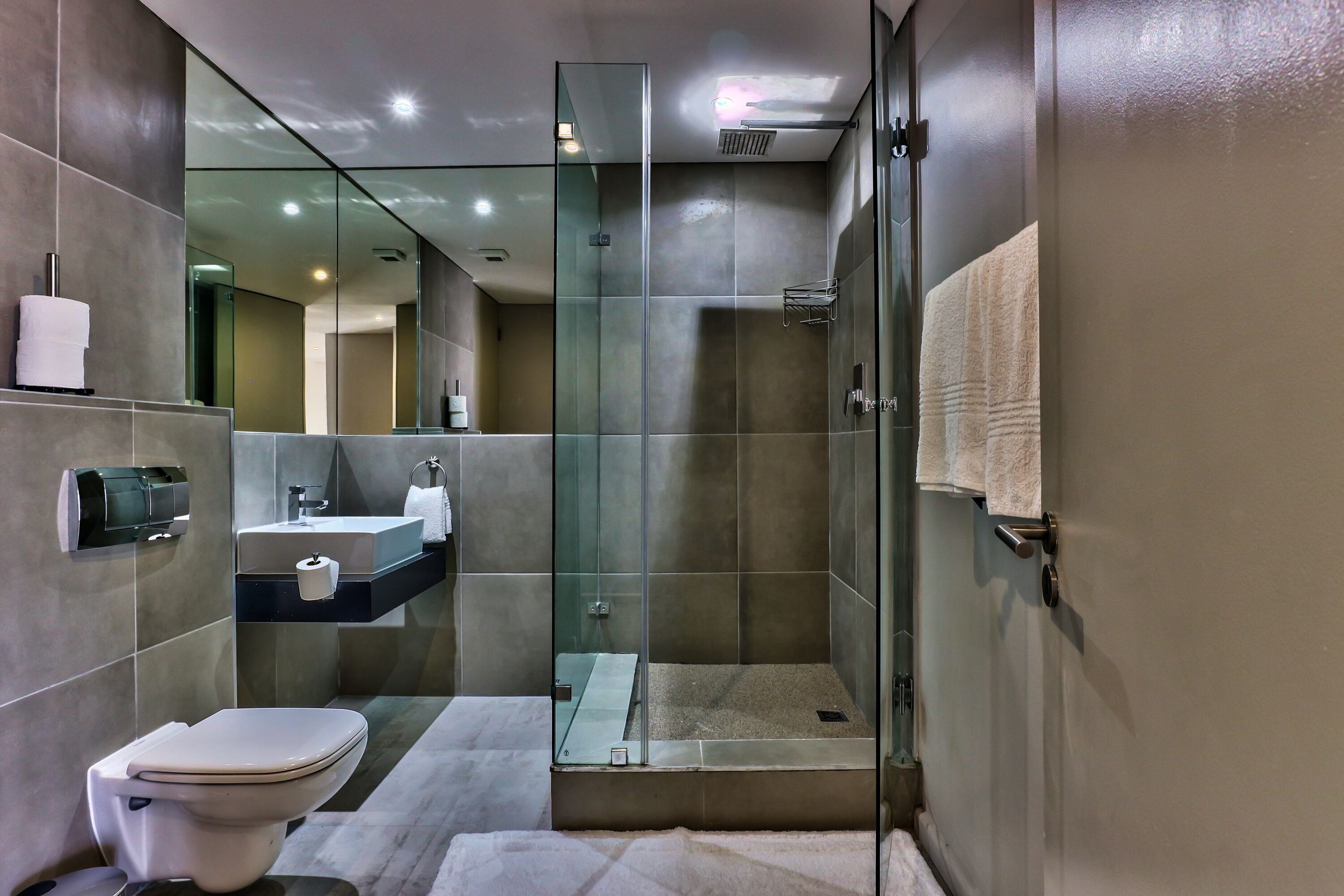 A modern bathroom with a toilet, sink, and glass-enclosed shower.