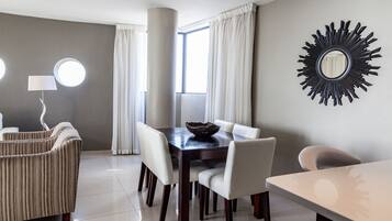 Un comedor moderno con una mesa de madera oscura, sillas blancas y un espejo decorativo en la pared.