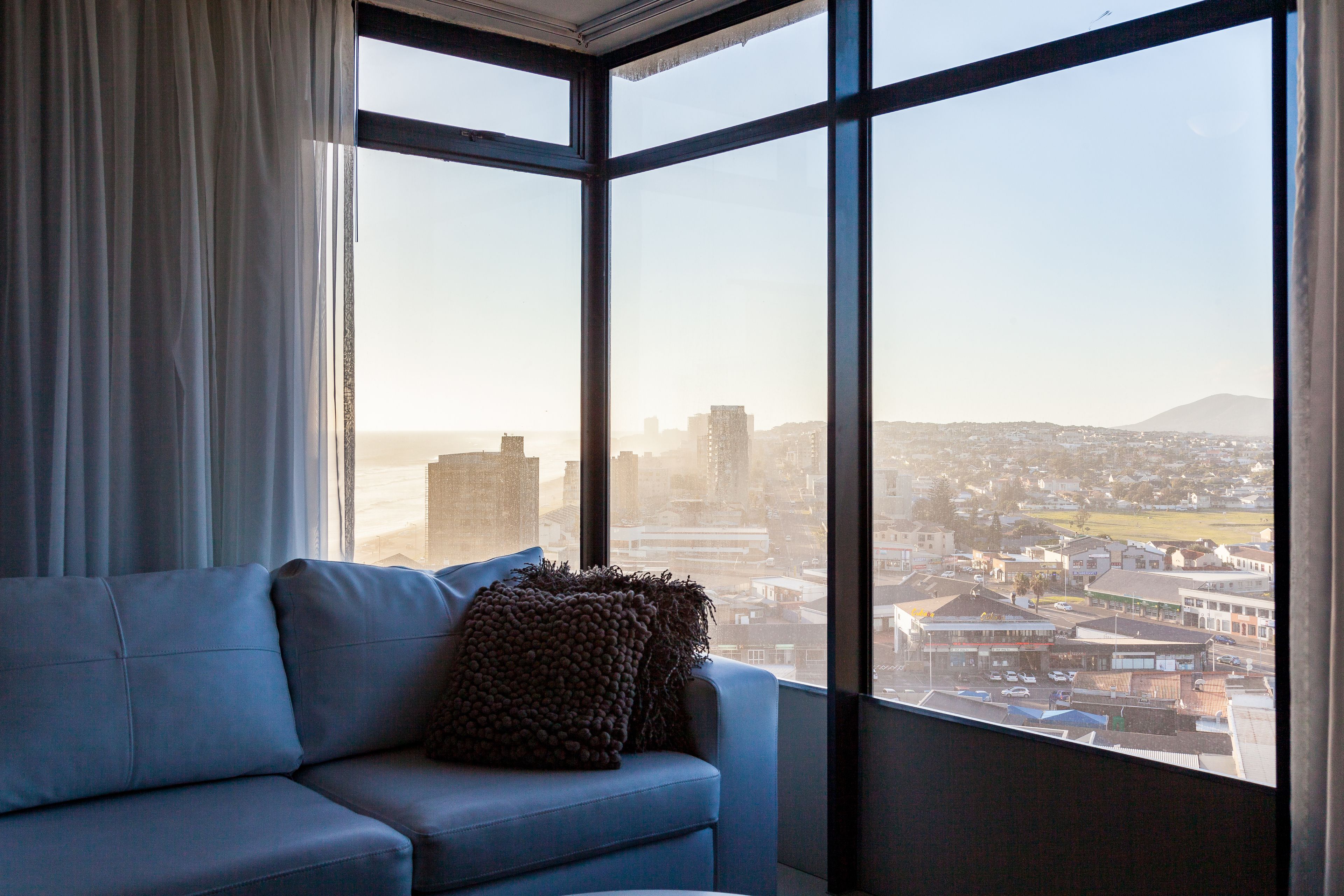A modern living room with a large window offering a city view.